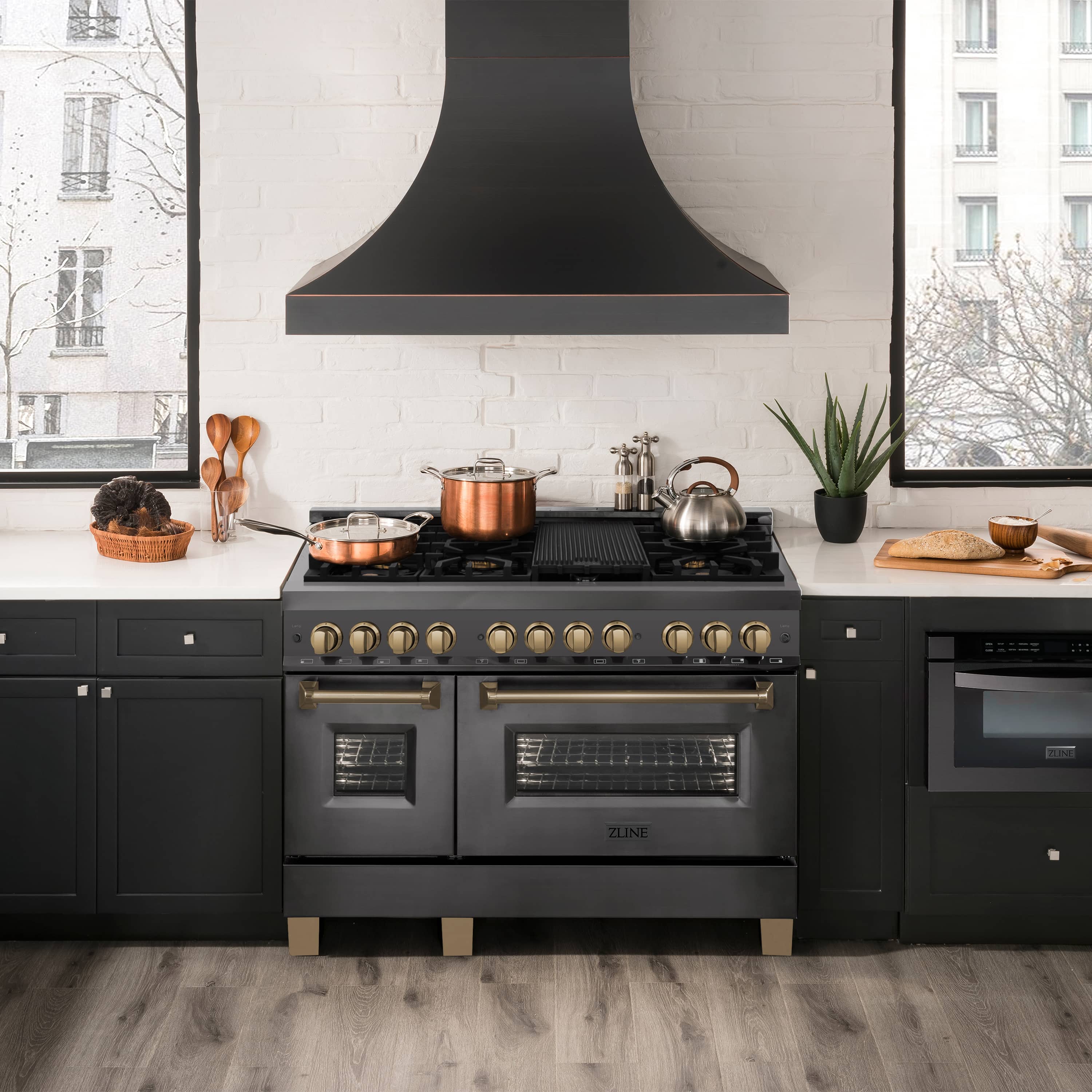 Black stainless dual fuel range with gold knobs and dual ovens, matching champagne bronze accents