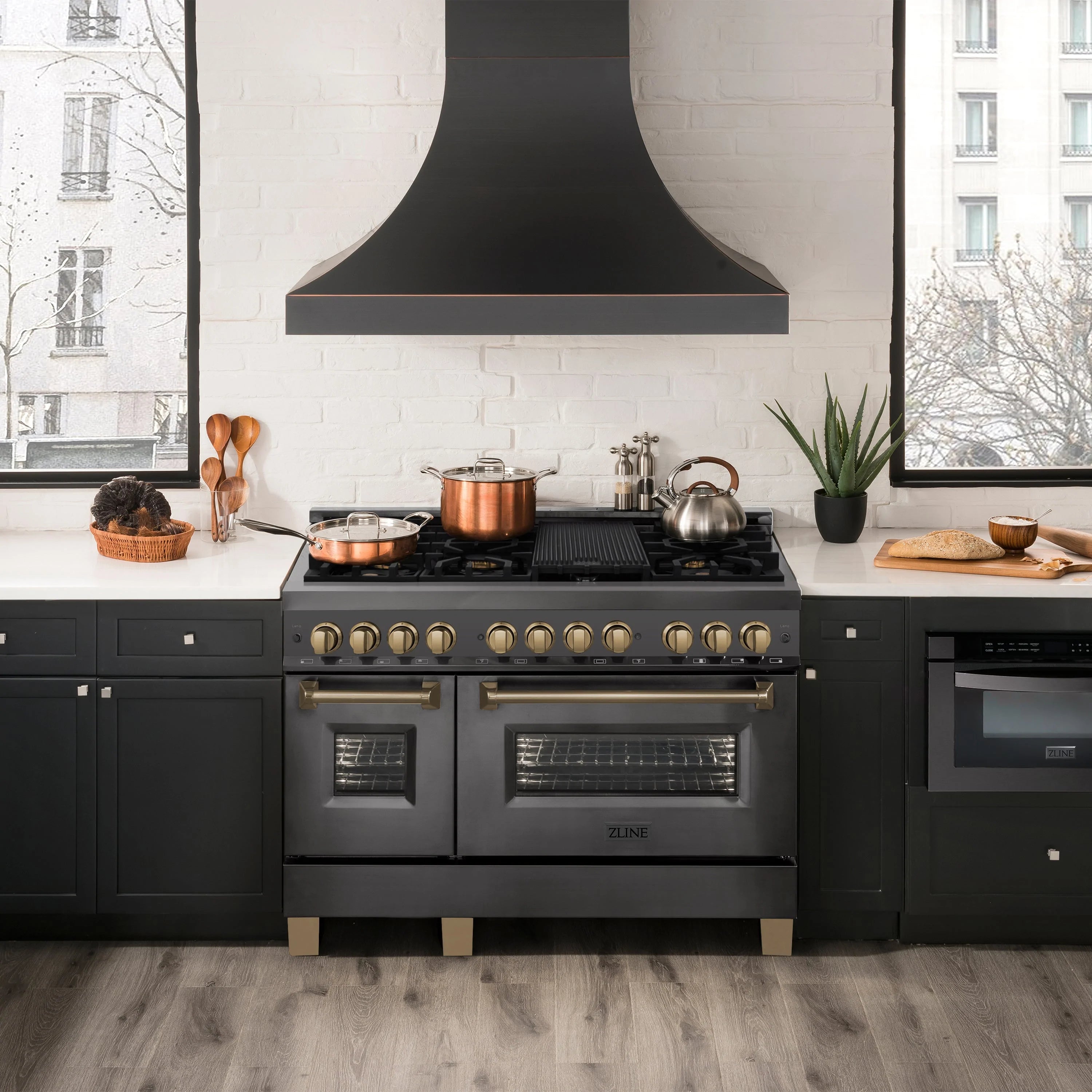 Dual fuel range in black with gold handles and control knobs in a kitchen
