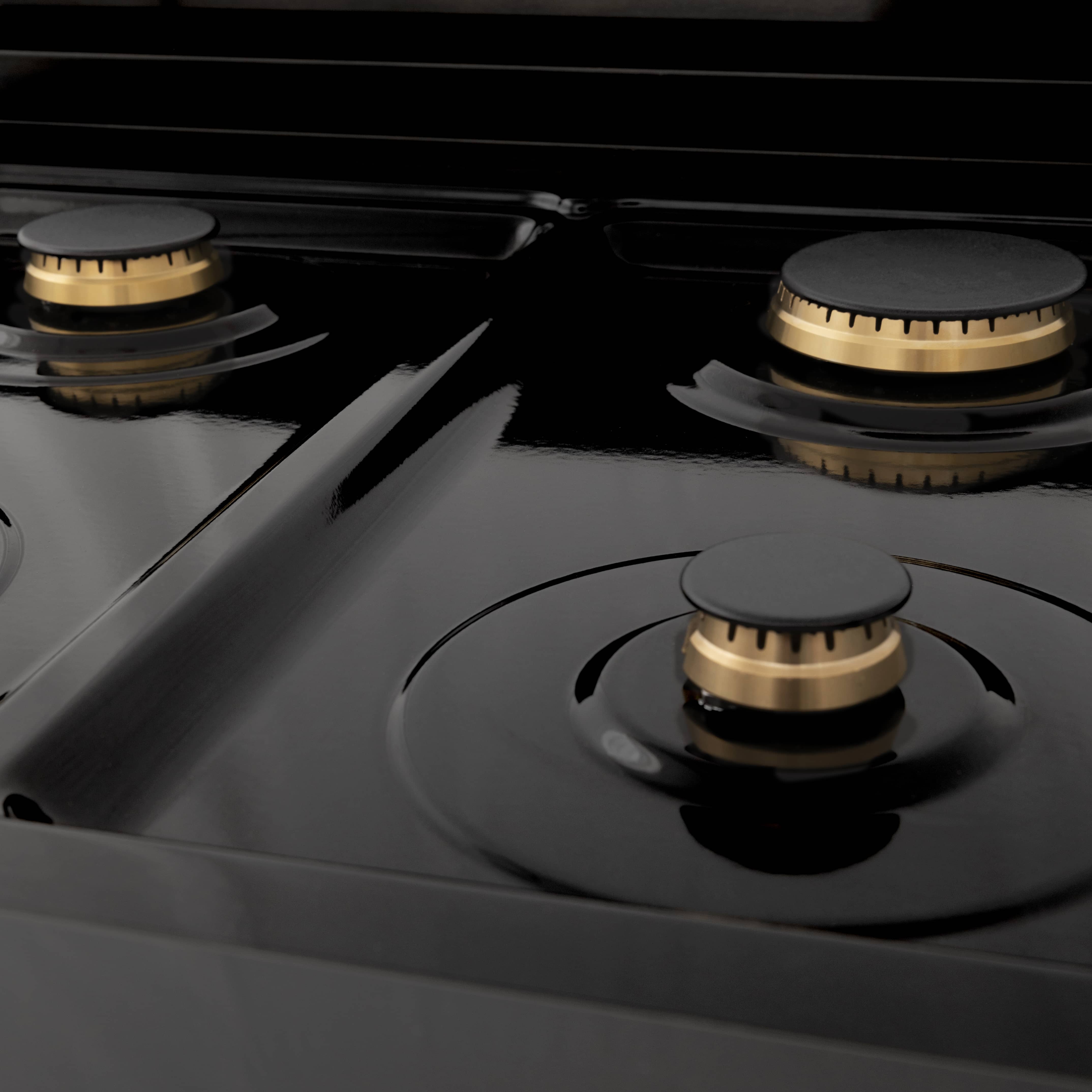 Black cooktop with three visible gas burners and gold-ring burner bases