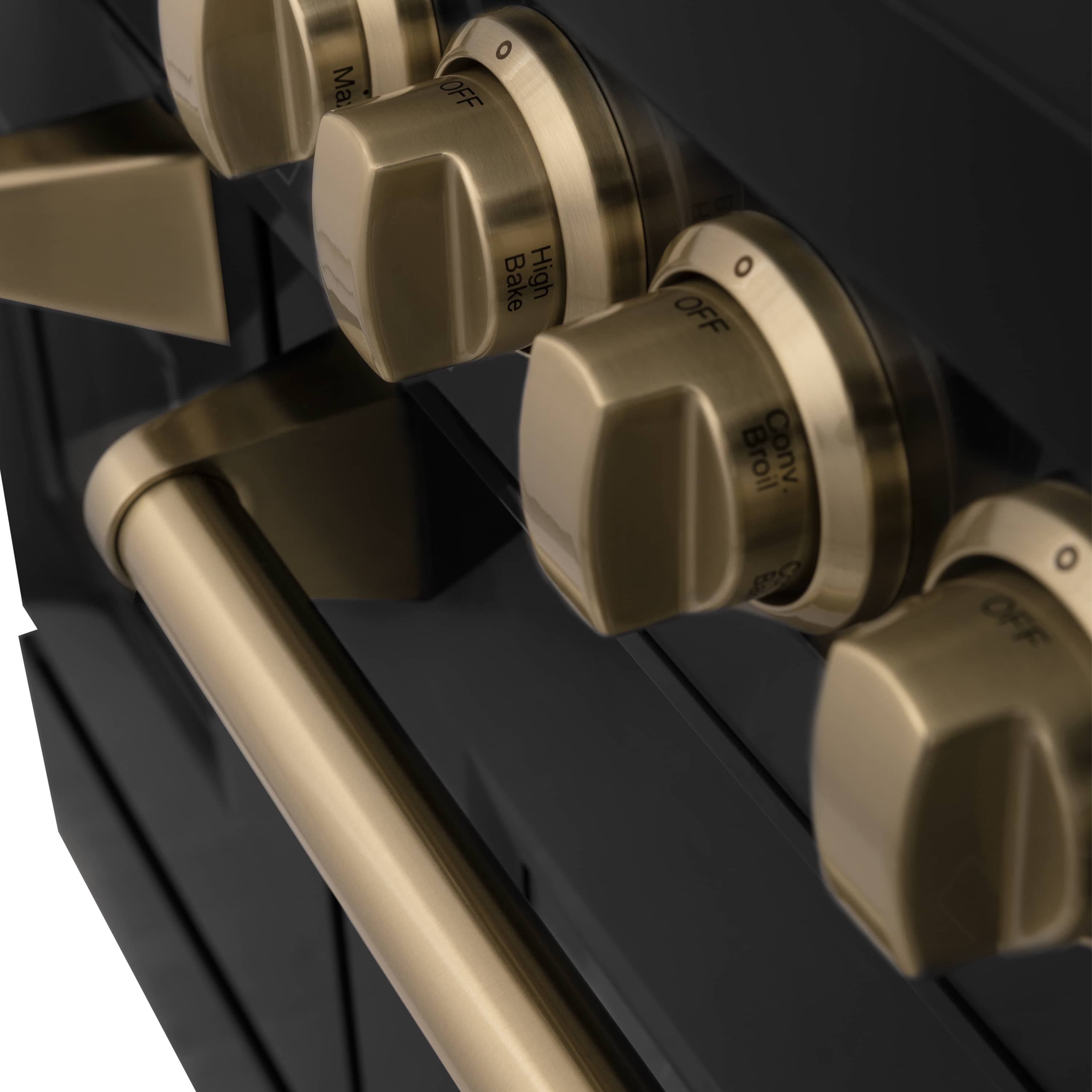 Close-up of champagne bronze range knobs with OFF markings on a black front