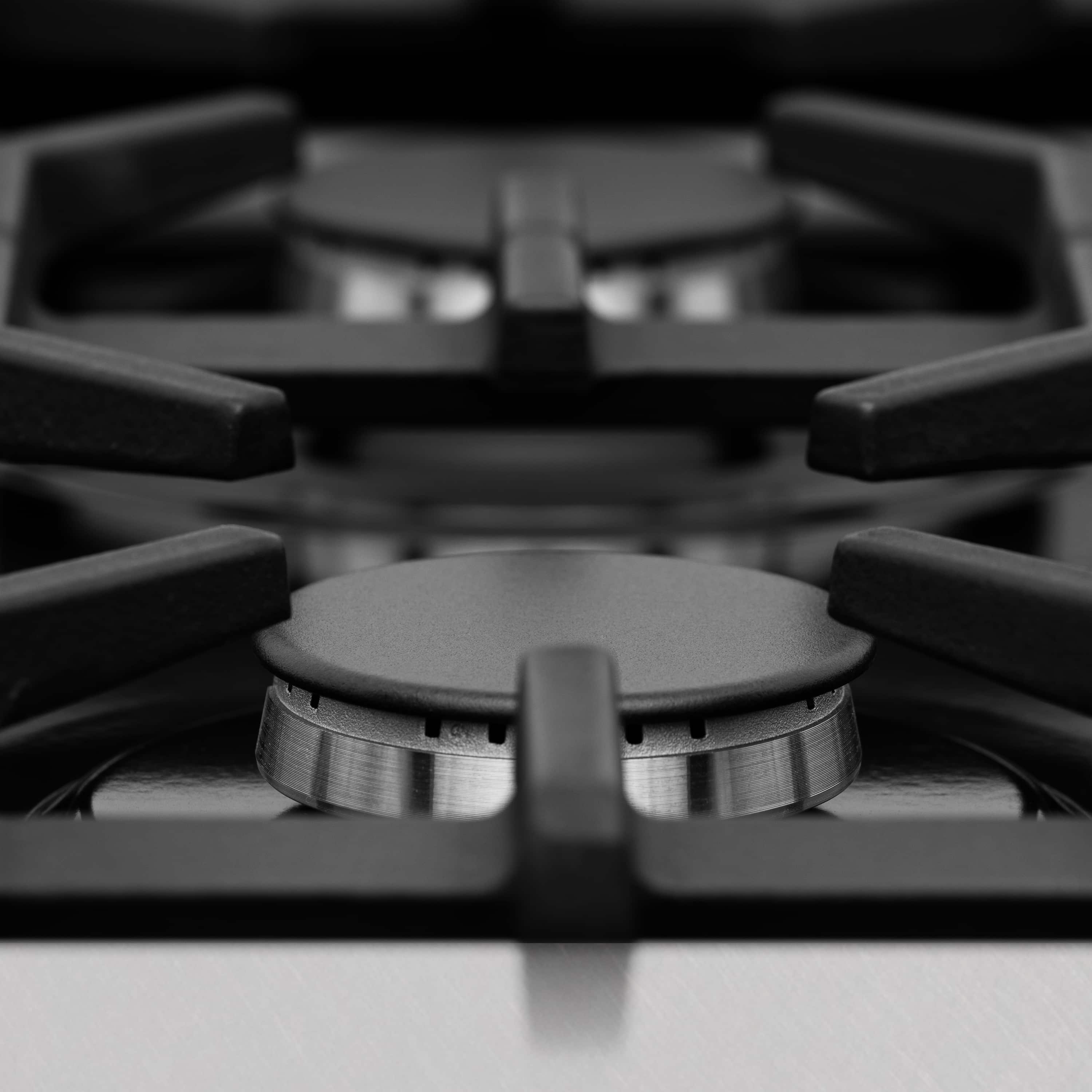 Gas cooktop burner head with round metal grate and black control knobs
