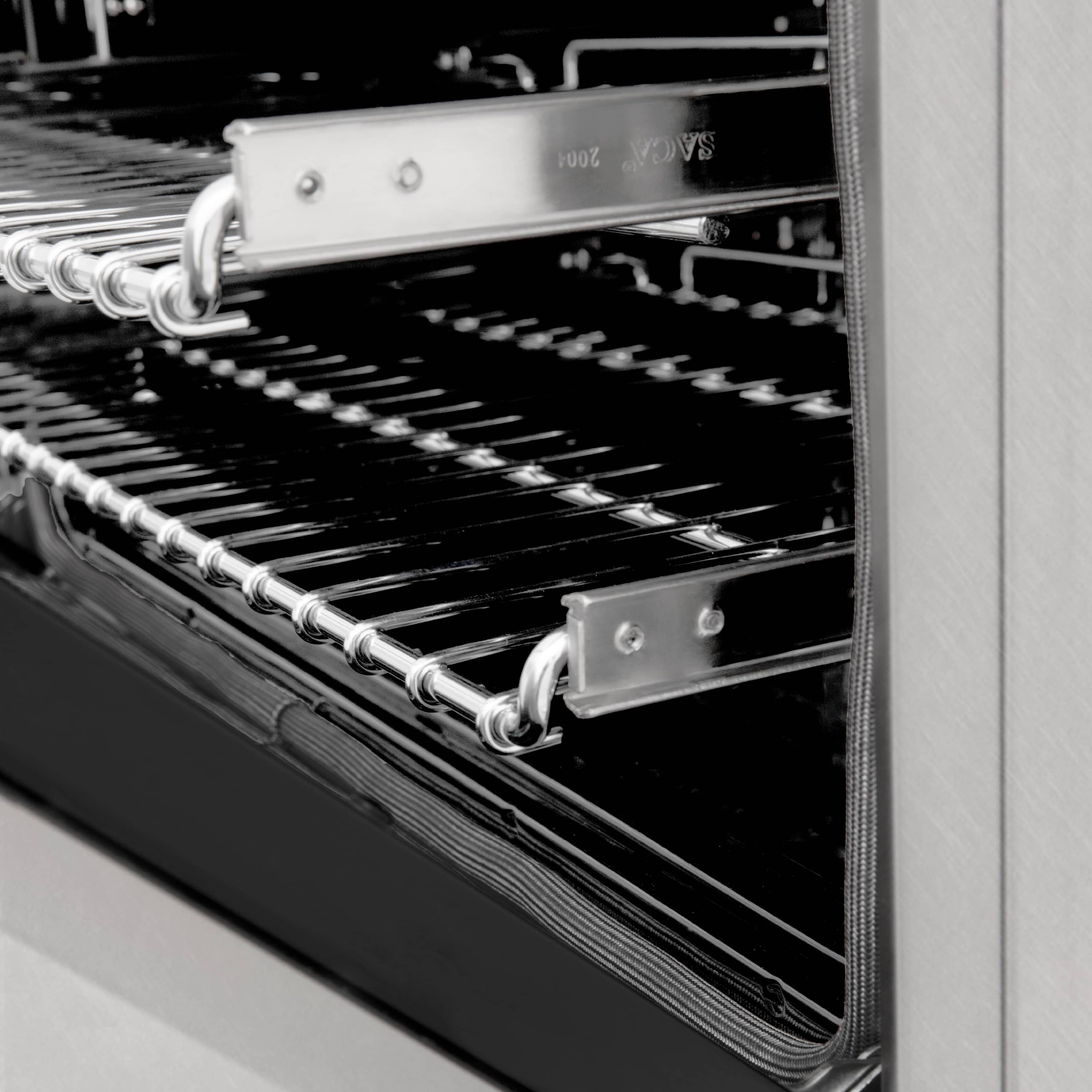 Close-up of oven burner grates and chrome rails inside dual fuel range