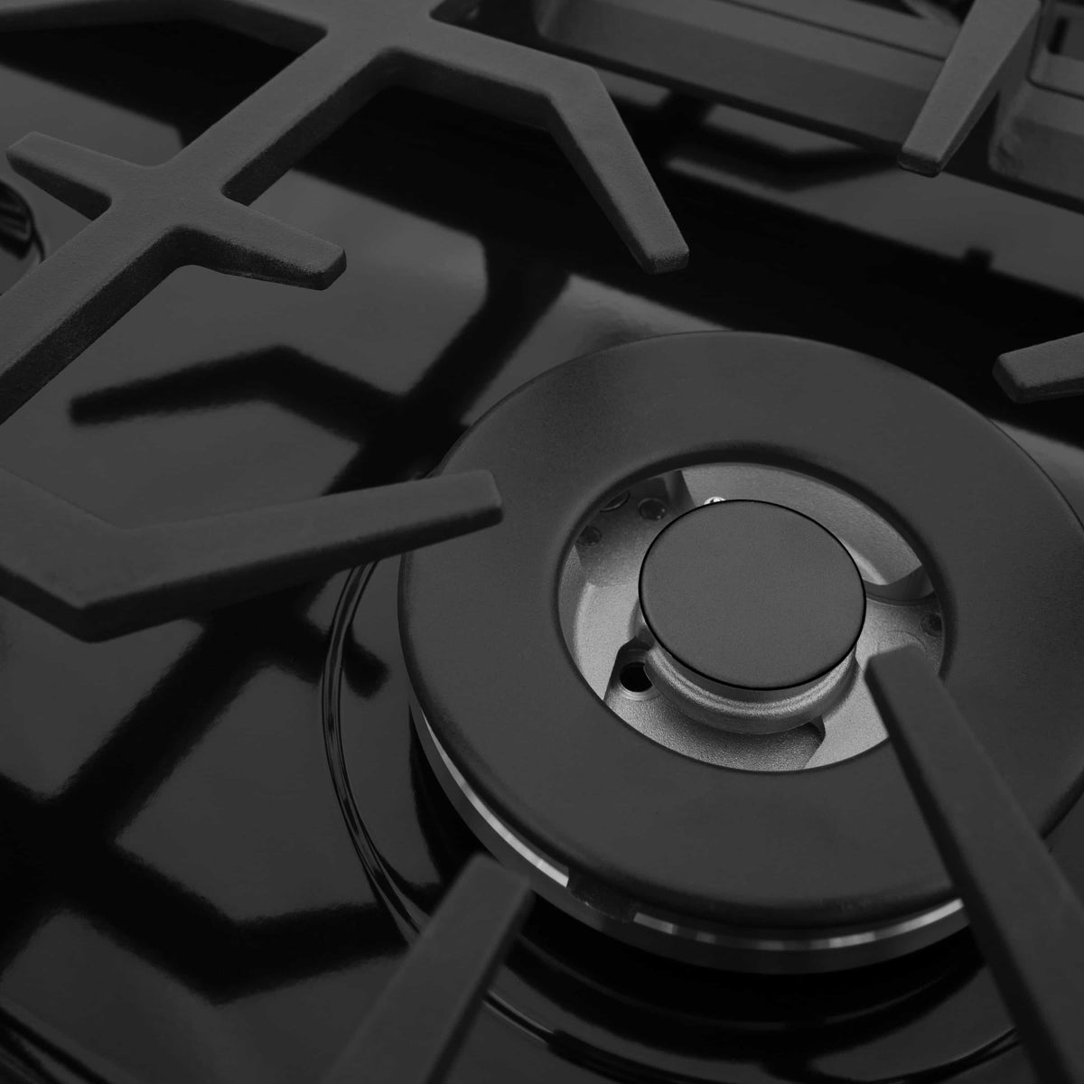 Close-up of a black gas burner with round burner cap and metal base ring