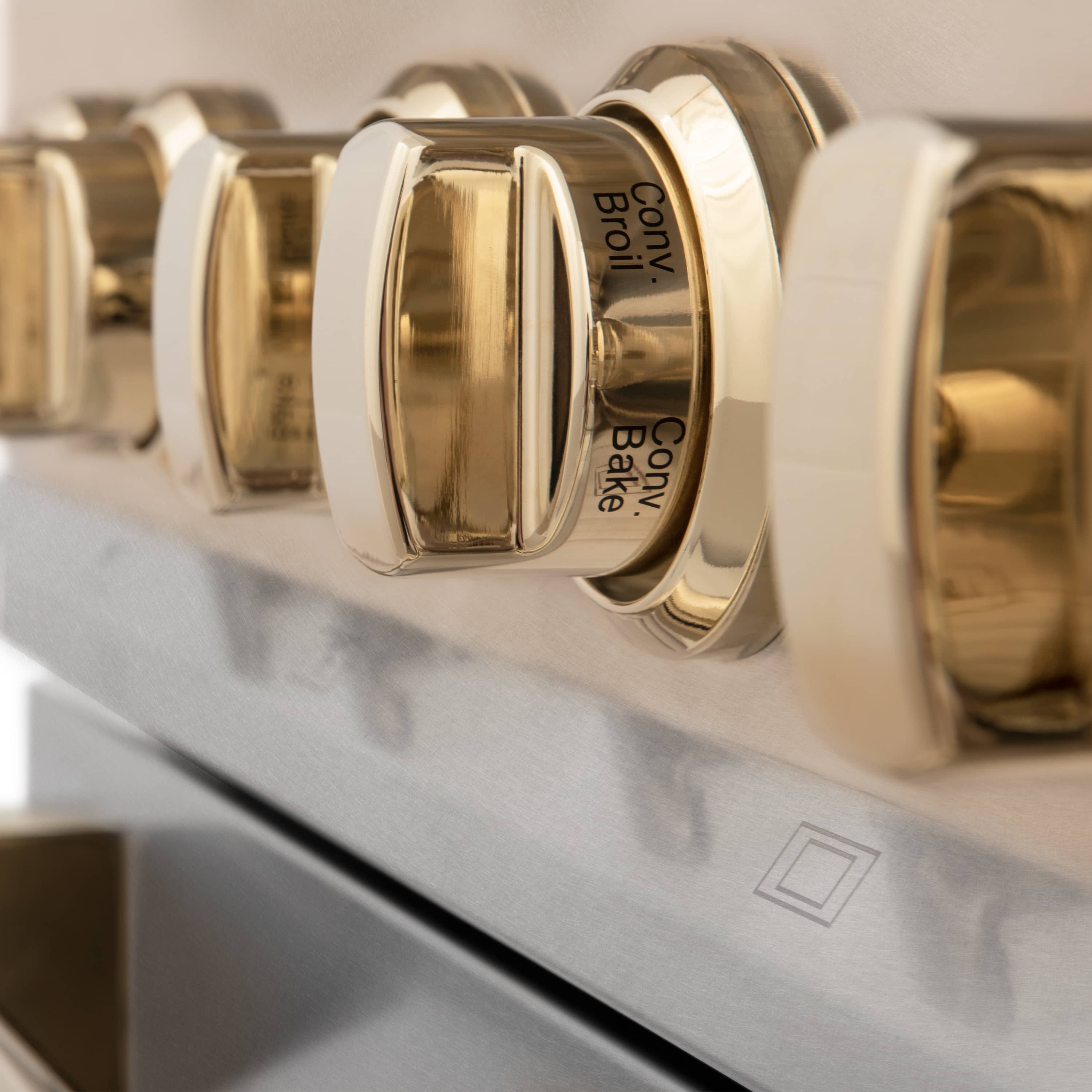Gold control knobs on satin stainless oven front with engraved center lettering