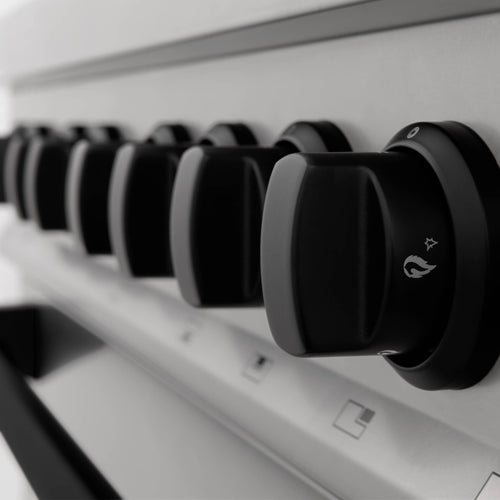 Close-up of black control knobs on a white dual fuel range cooktop