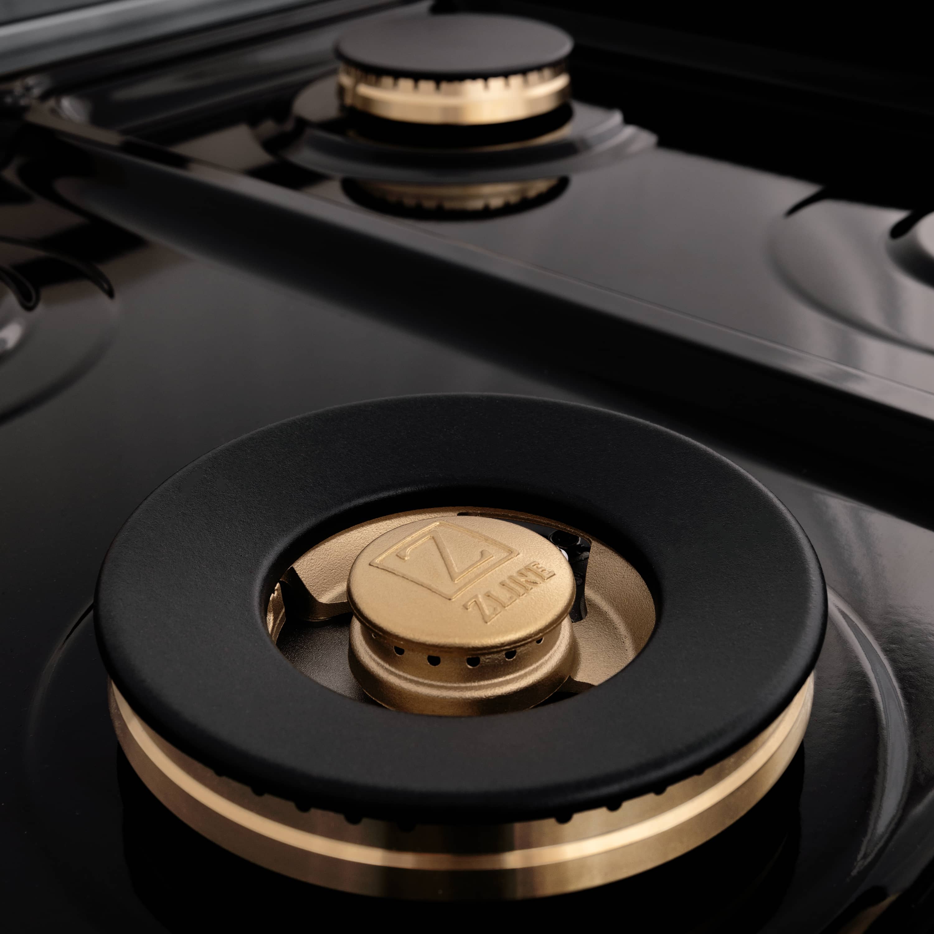 Close-up of black gas burner with gold-accent cap on stainless cooktop