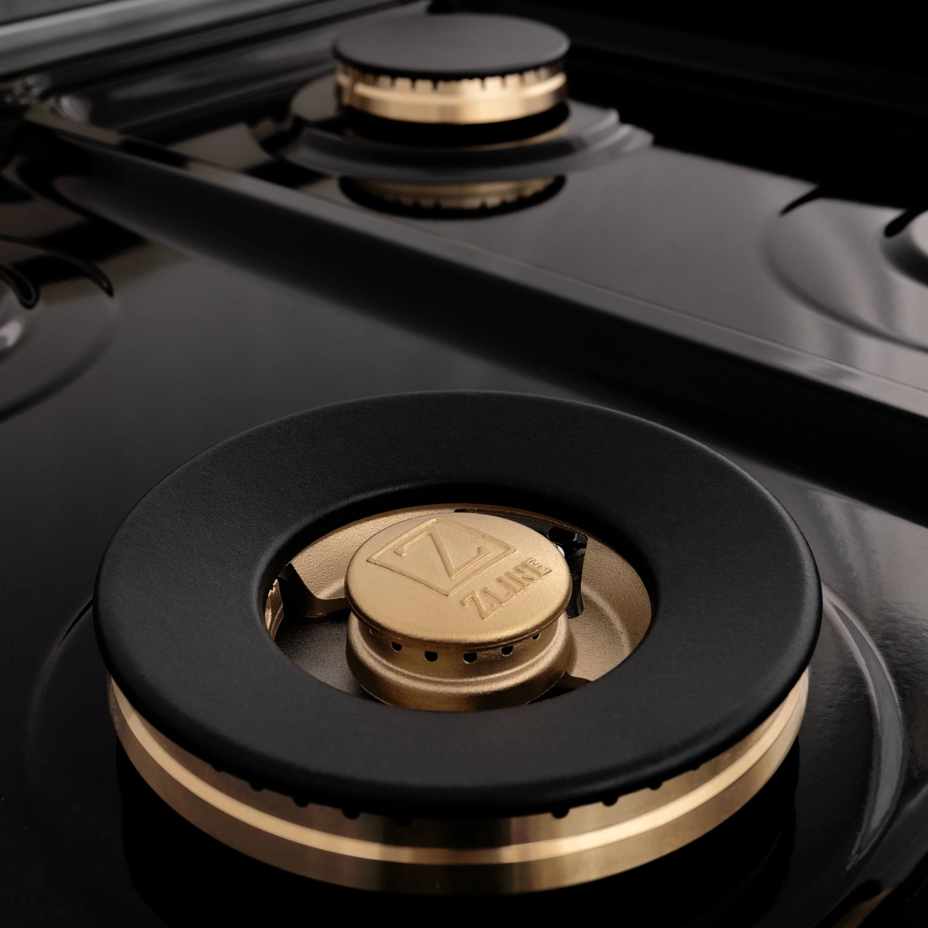 Dual fuel range burner with black cooktop and gold-trimmed cap