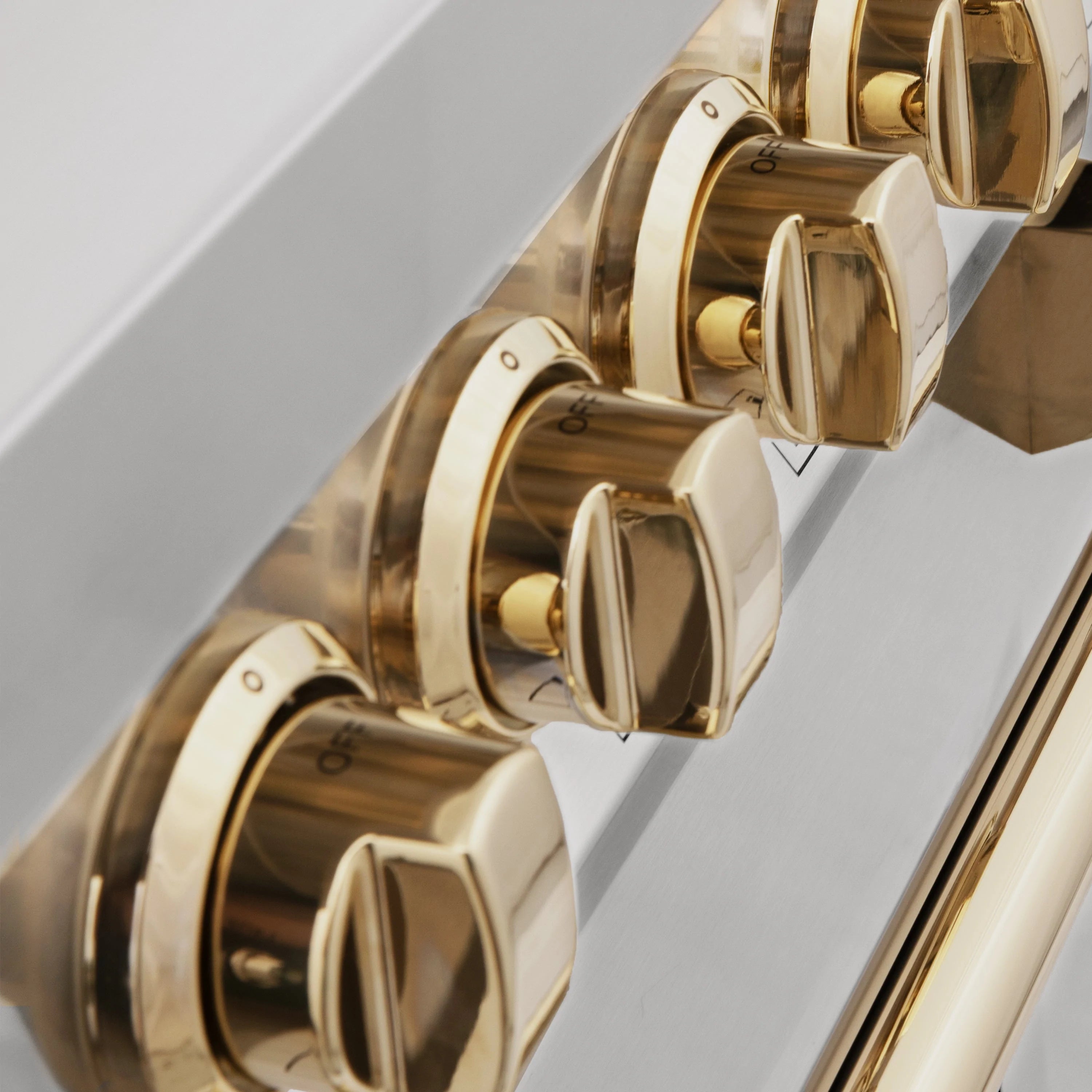 Dual fuel range gold control knobs on a stainless steel panel