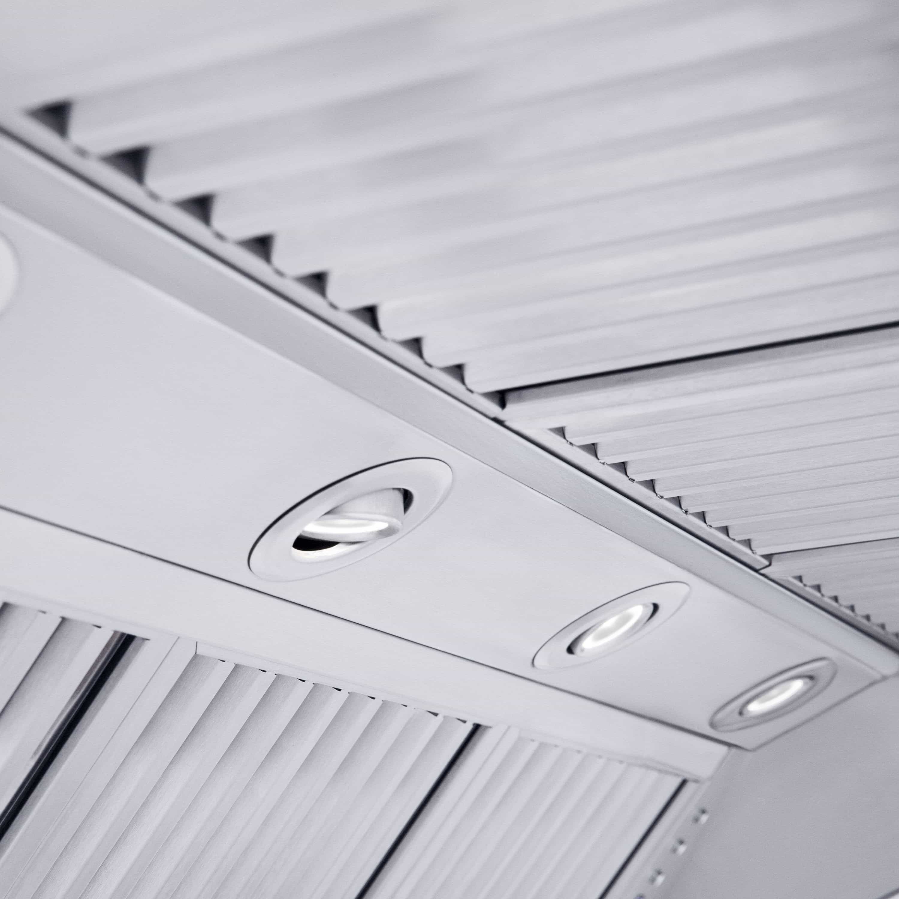 Range hood vent underside with ribbed metal baffles and three recessed circular light lenses