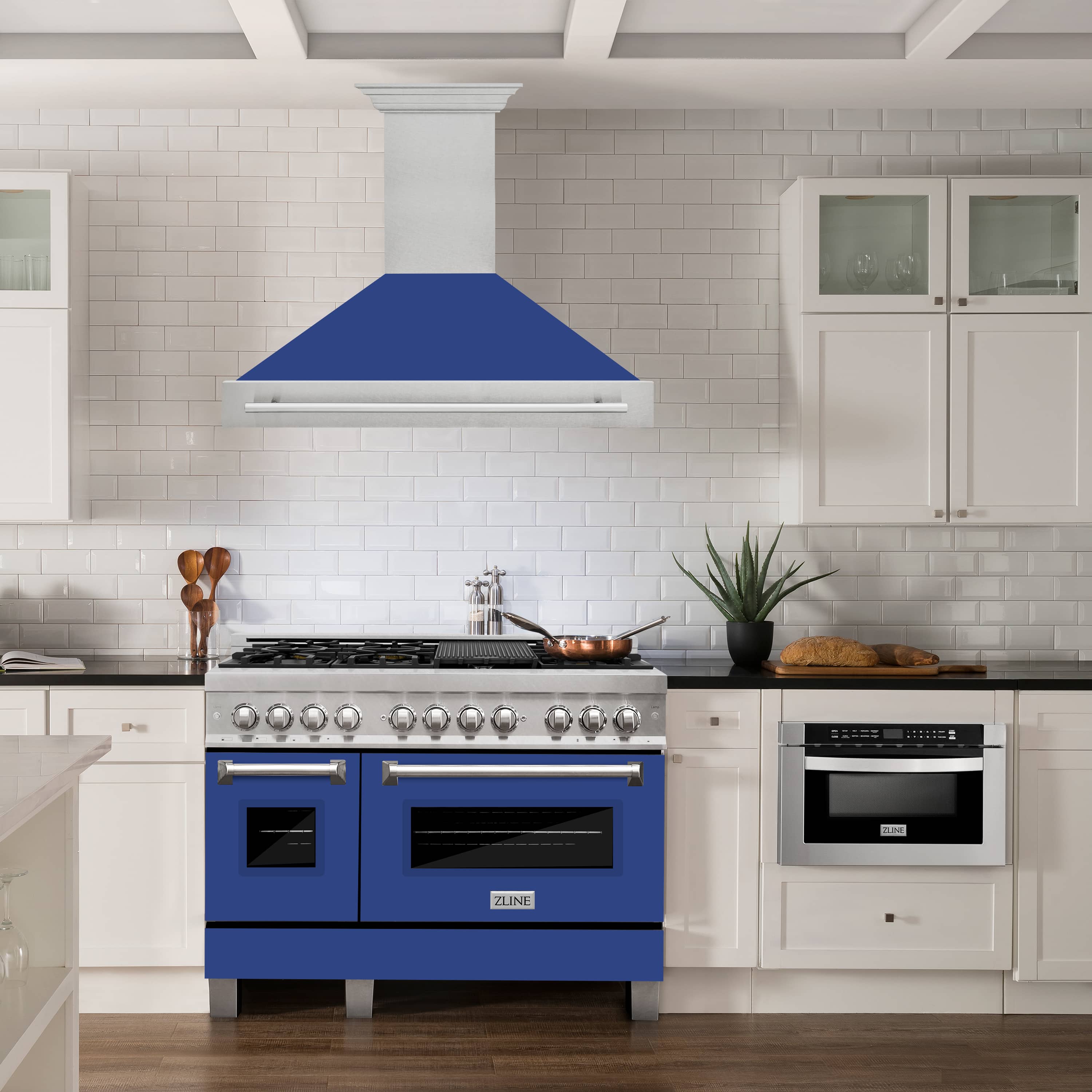 Wall-mount range hood above a cooktop, blue matte shell with stainless steel chimney