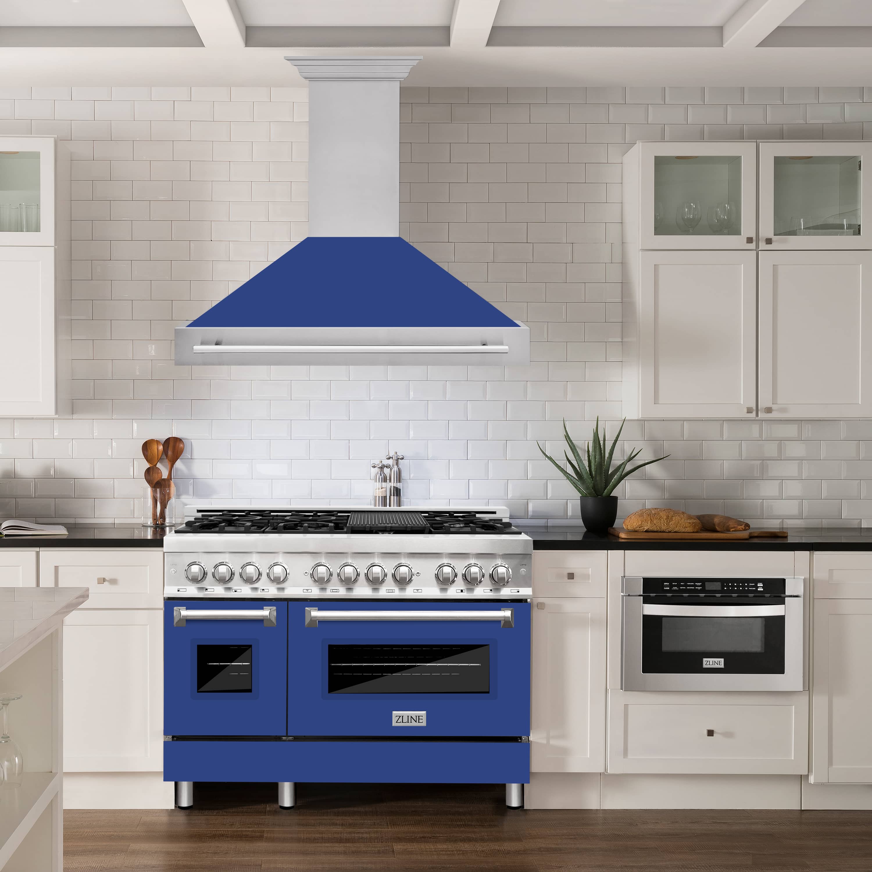Blue matte wall mount range hood over stainless kitchen range with bar handle