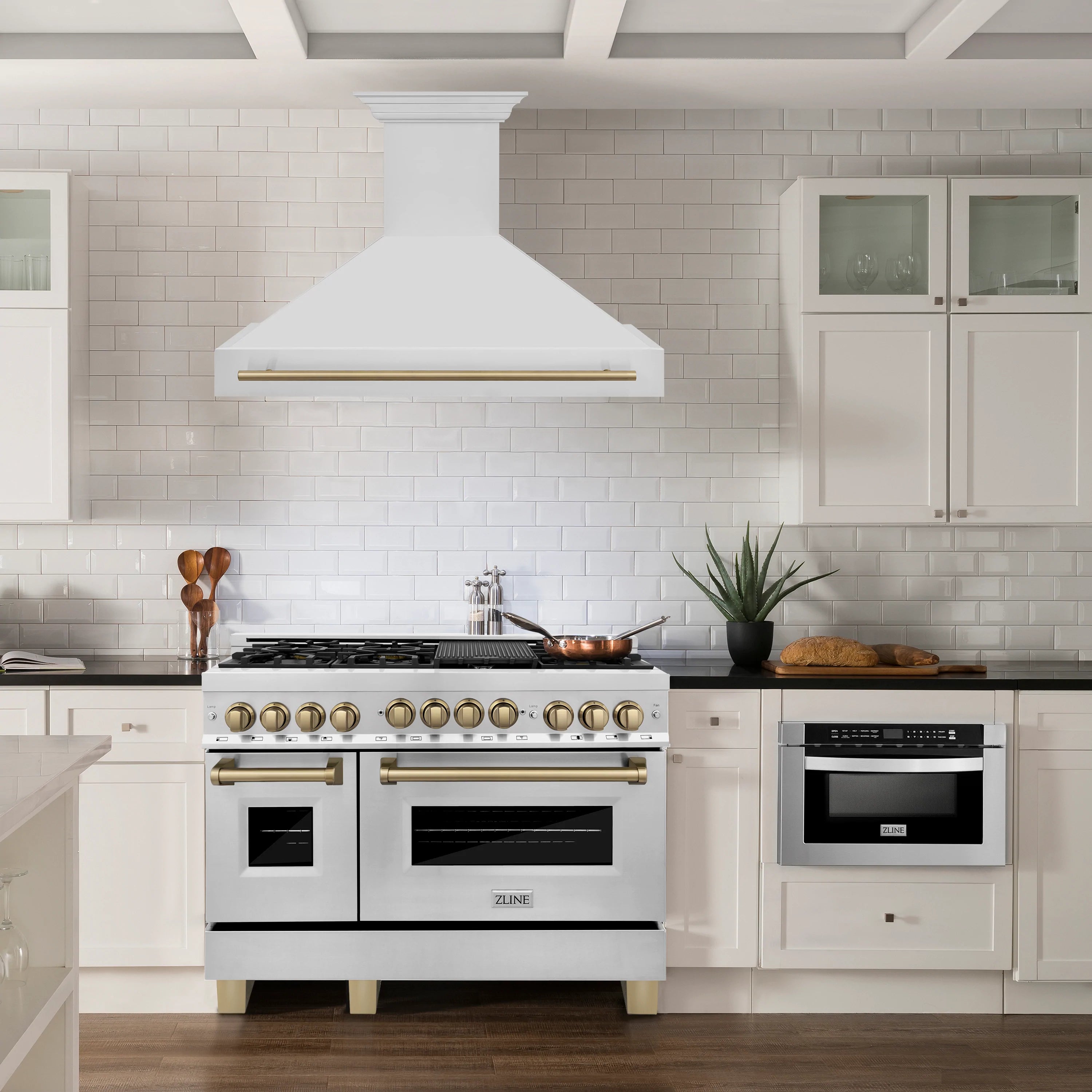 Stainless dual fuel range with wall hood in a white kitchen setup