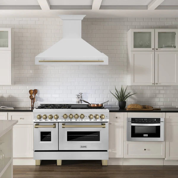 Dual fuel range with wall mounted hood and brass knobs, white finish