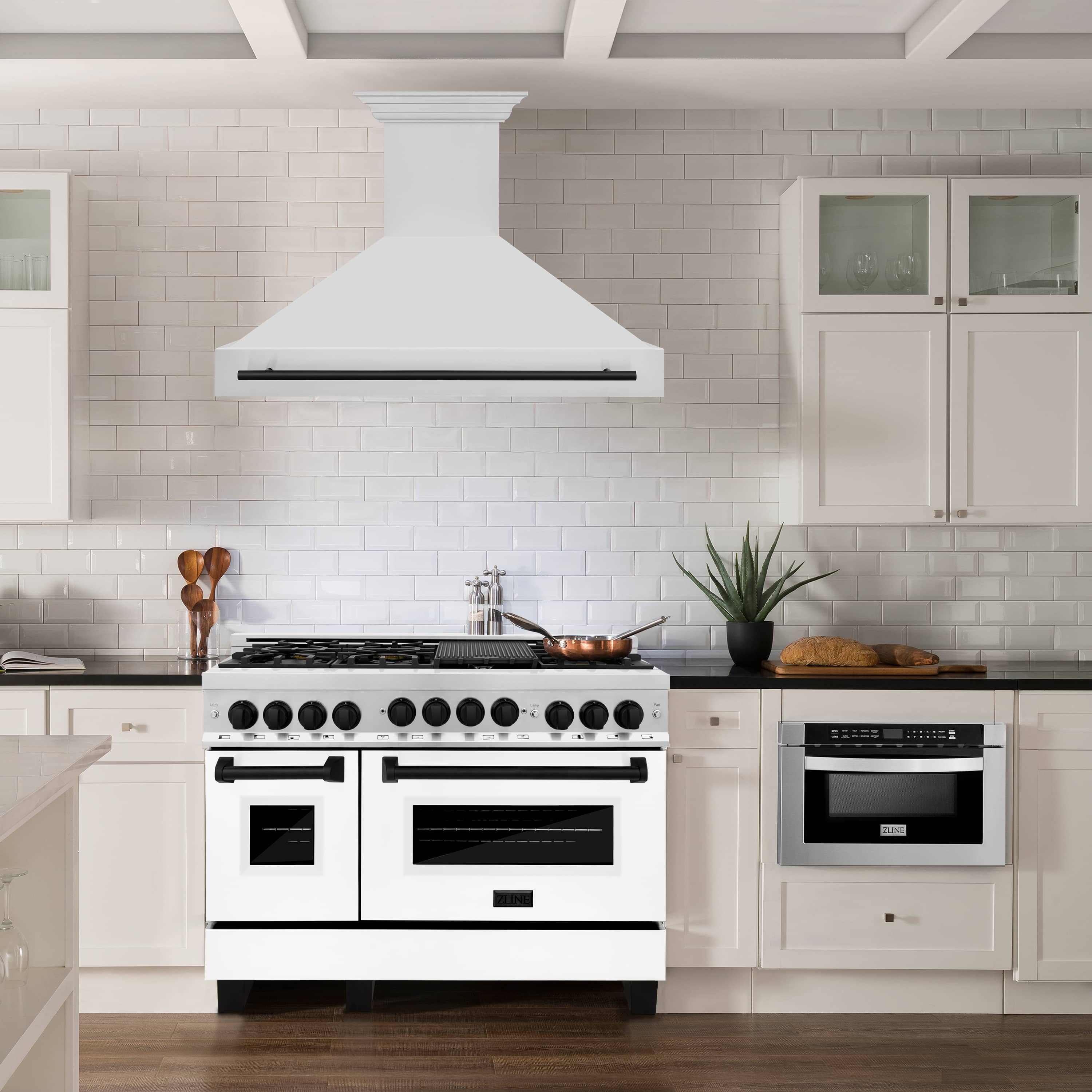 Stainless steel wall mount range hood with matte black handle above cooktop in kitchen.