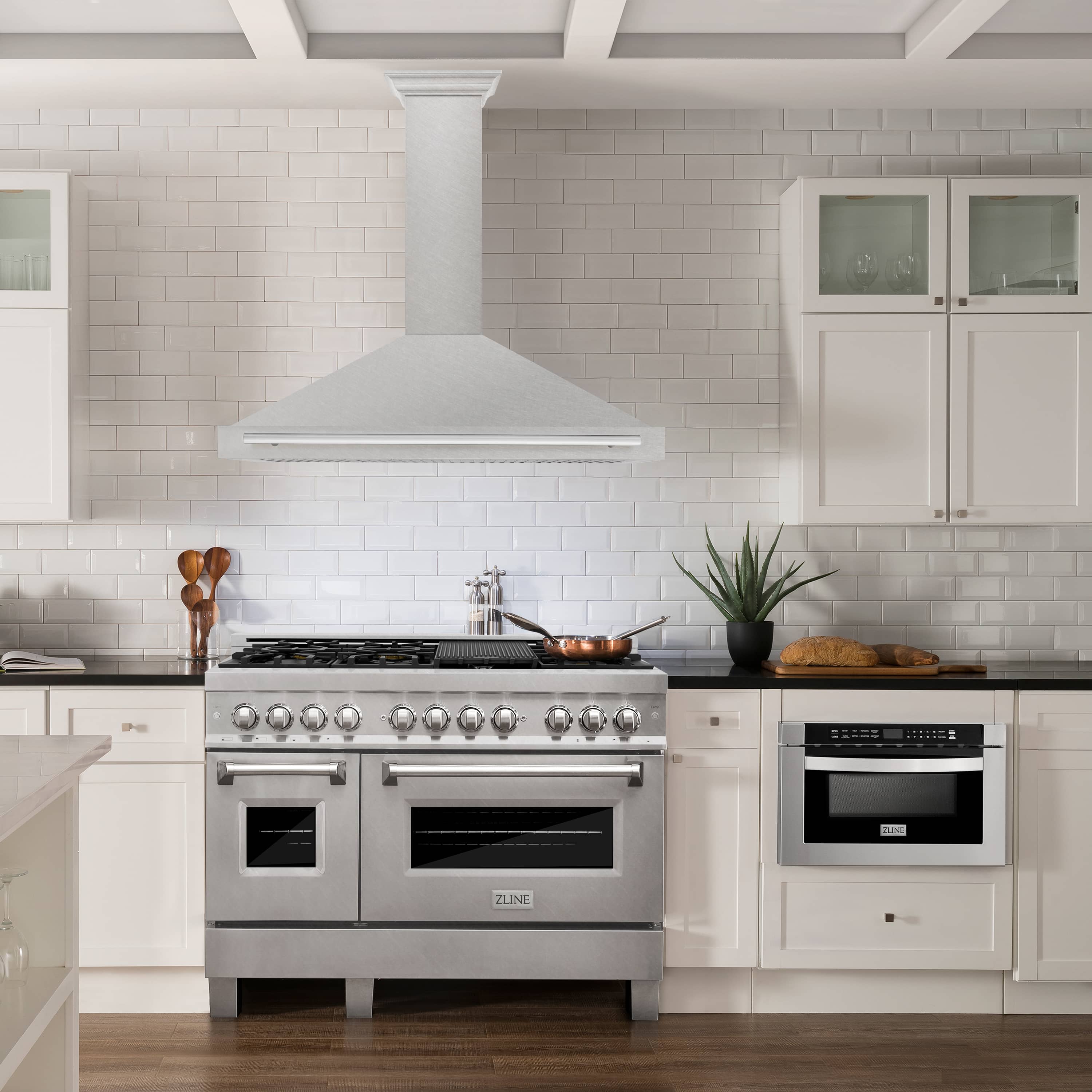 Satin stainless steel wall-mounted range hood above kitchen range, chimney style