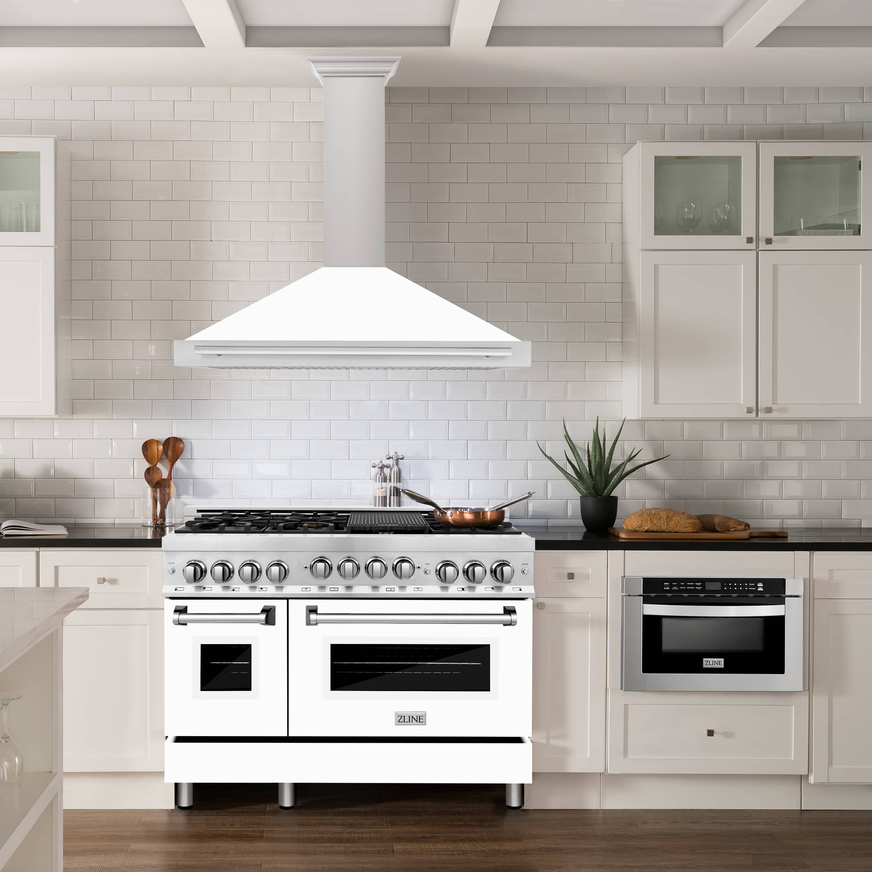 Wall-mounted range hood with white matte chimney and stainless canopy above cooktop