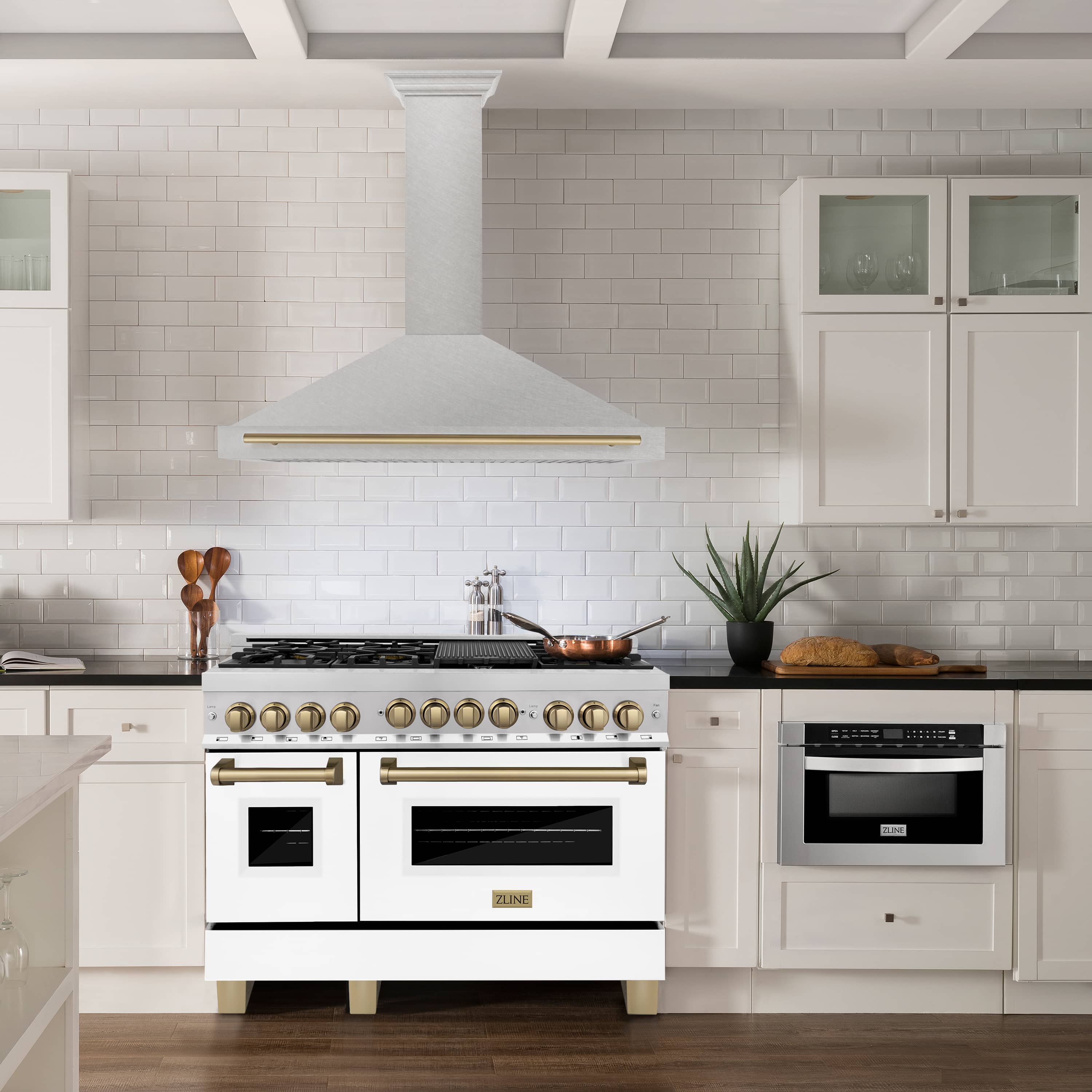 Wall-mounted range hood with satin stainless chimney and champagne bronze trim bar