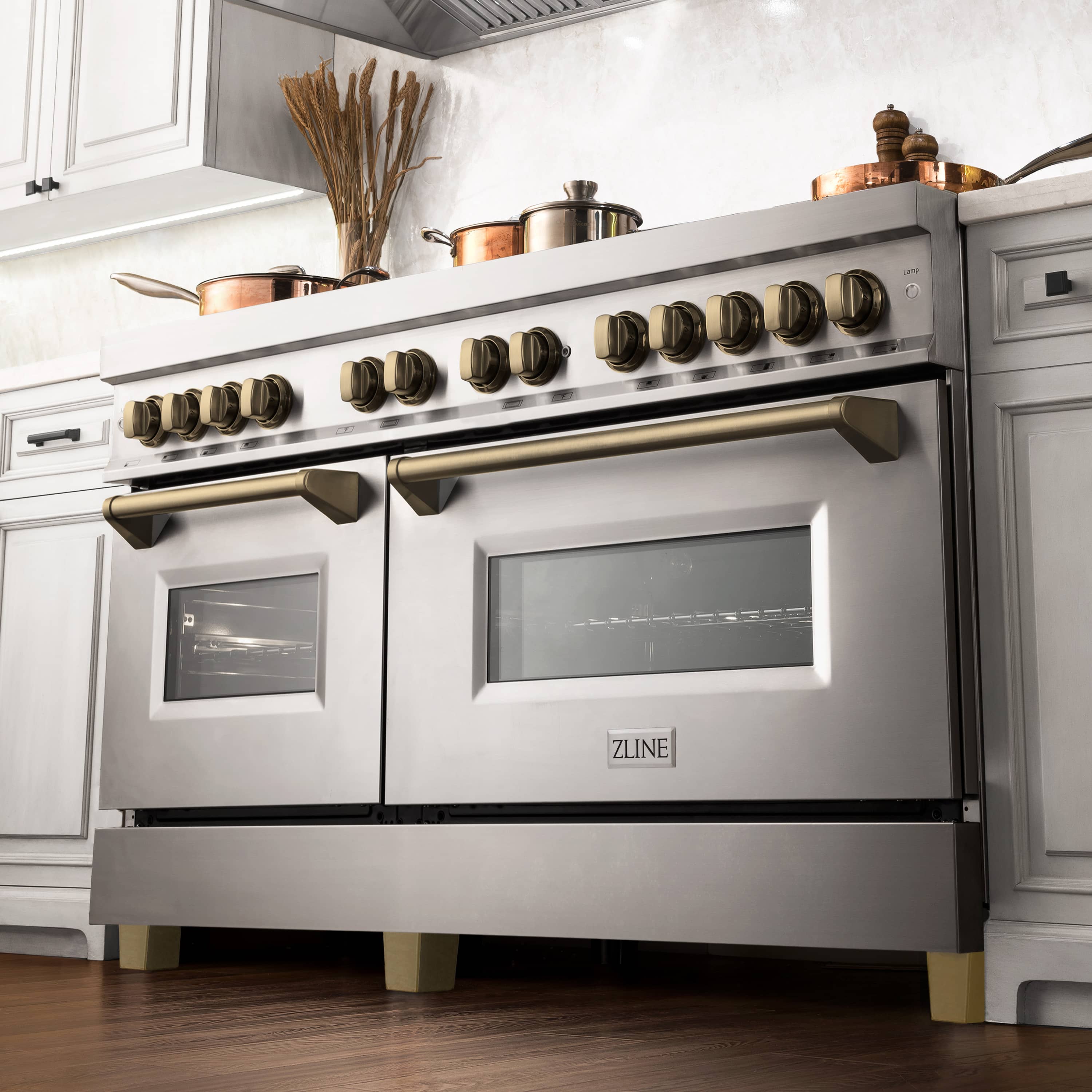 Dual fuel range front with bronze knobs, gold handles, and glass oven doors
