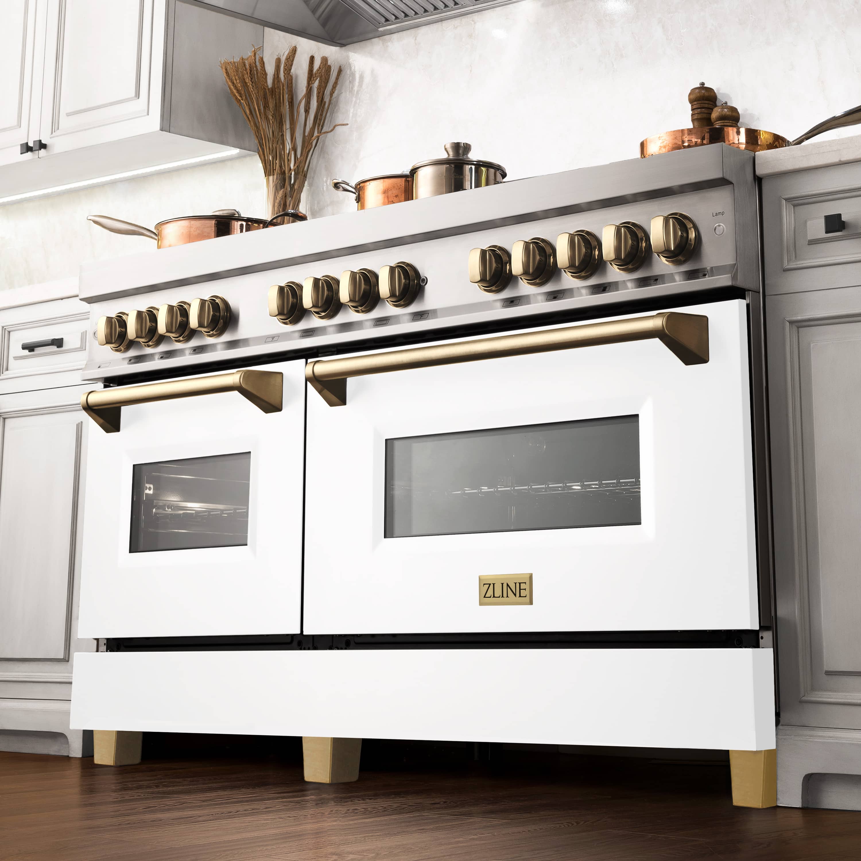 White dual fuel range with gold control knobs, gold handles, and two black windows