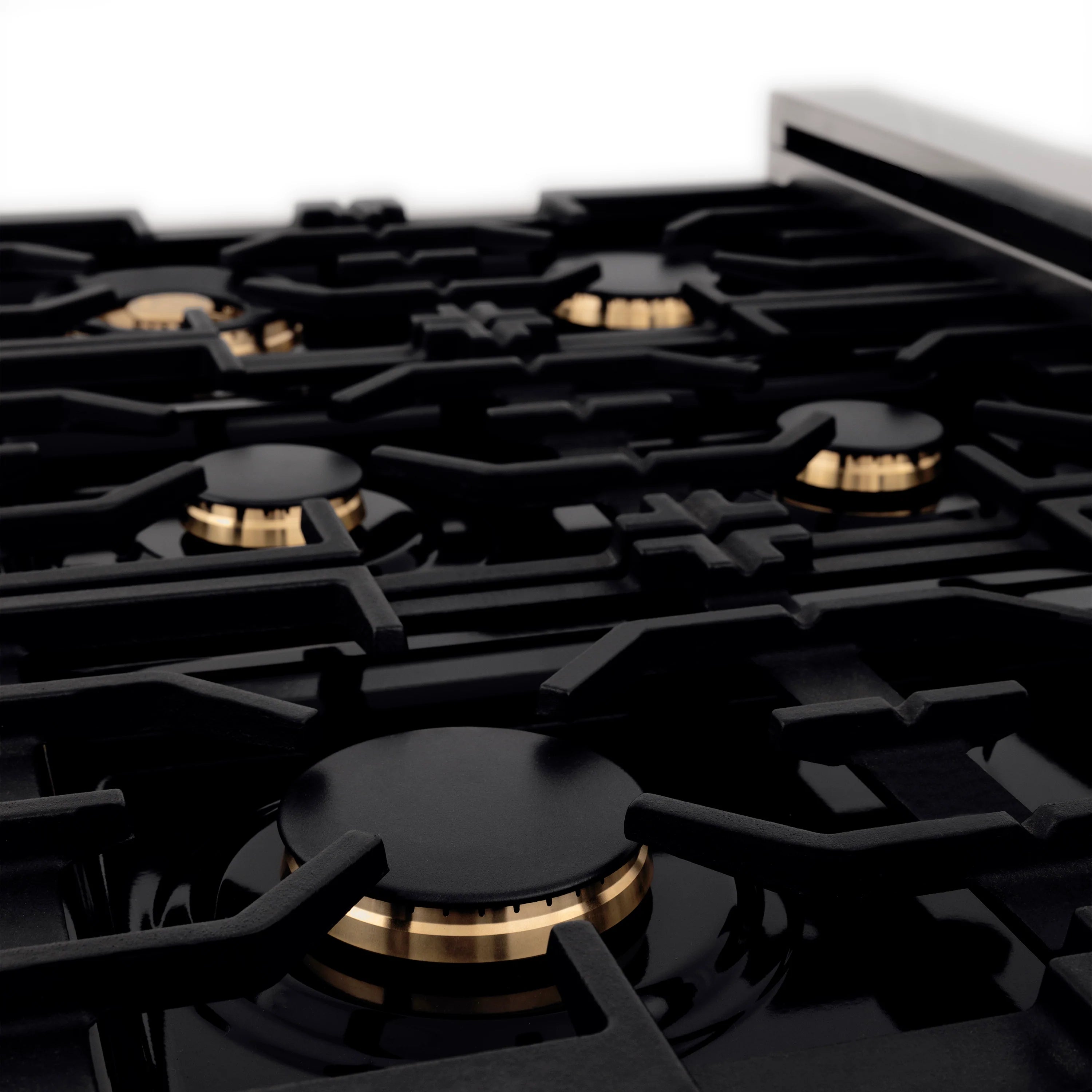 Close-up of black gas cooktop grates with round burners and champagne bronze accents