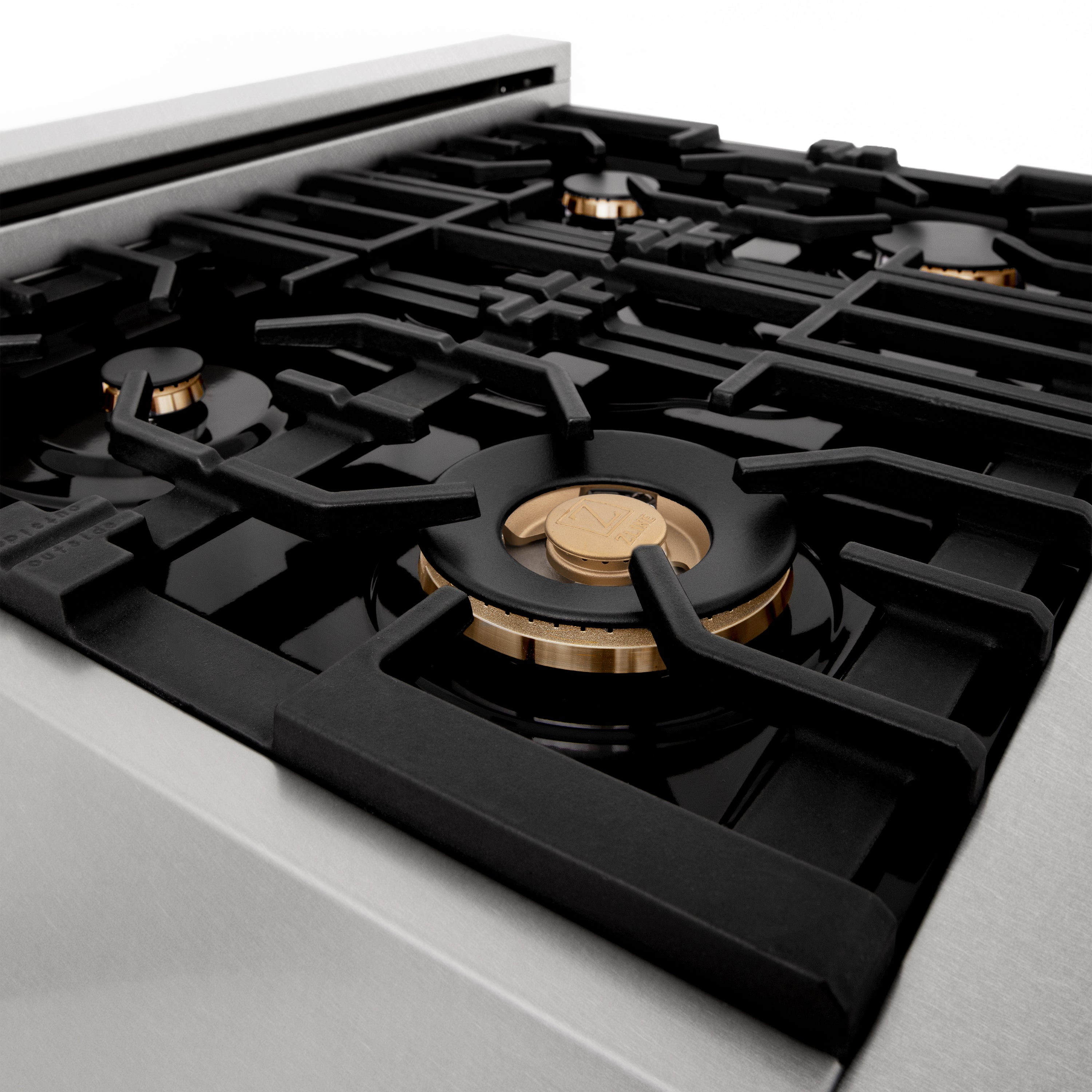 Close-up of black cooktop grates with brass-colored gas burner cap