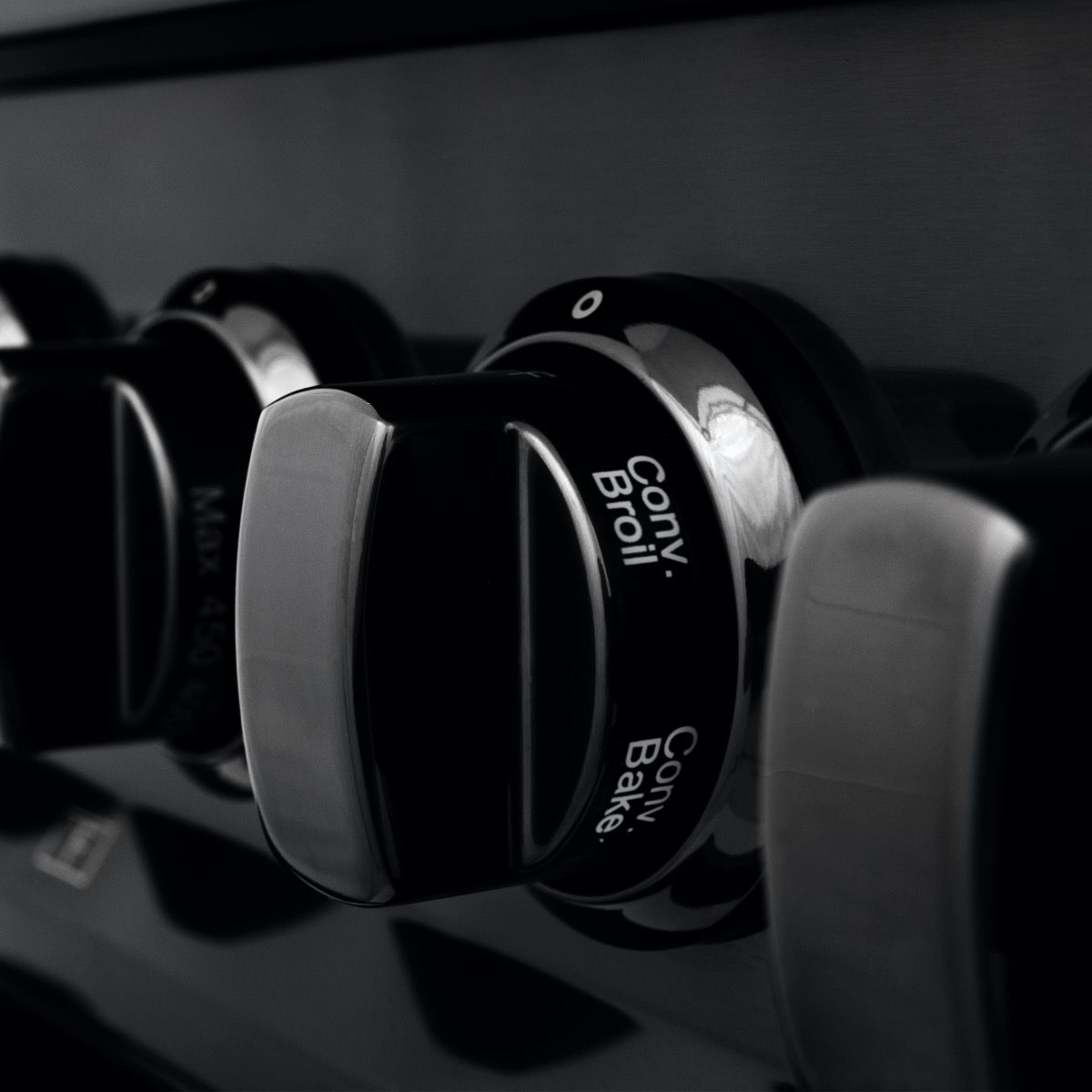 Black stainless dual fuel range knobs with brass burner caps and control markers
