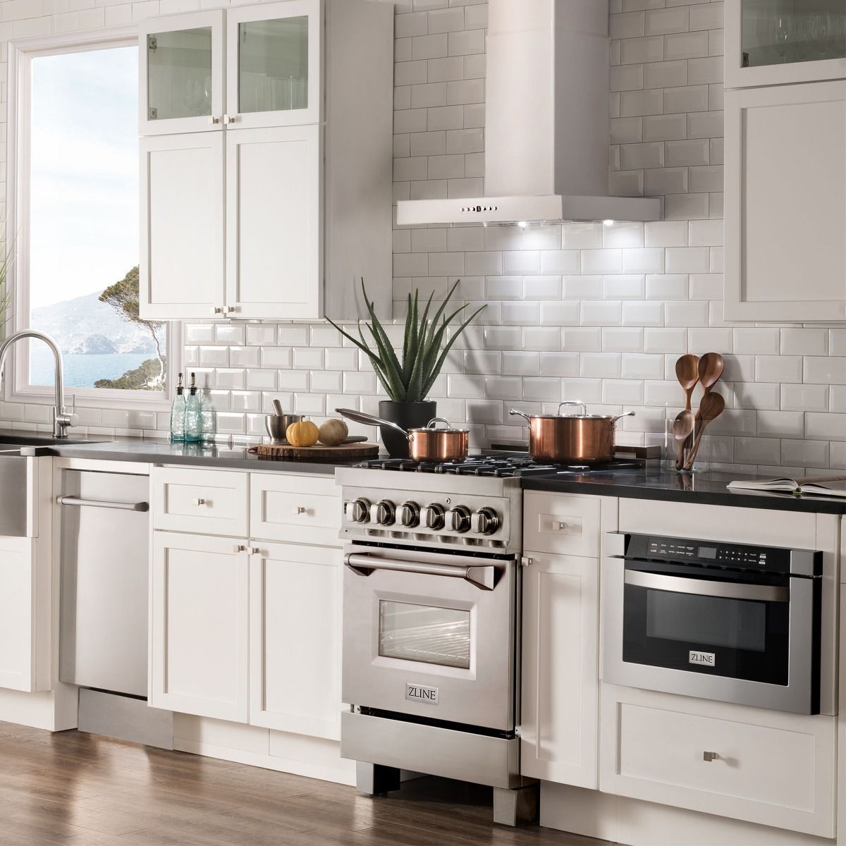 Stainless steel wall-mount range hood above a multi-burner gas cooktop