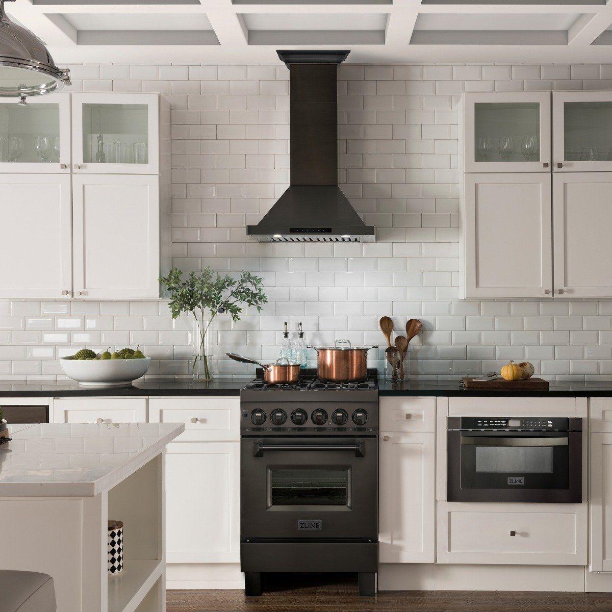 Black wall mount range hood above a kitchen cooktop, with chimney and vent canopy.