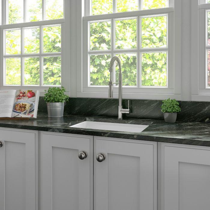 White single-bowl fireclay kitchen sink with deck-mounted faucet