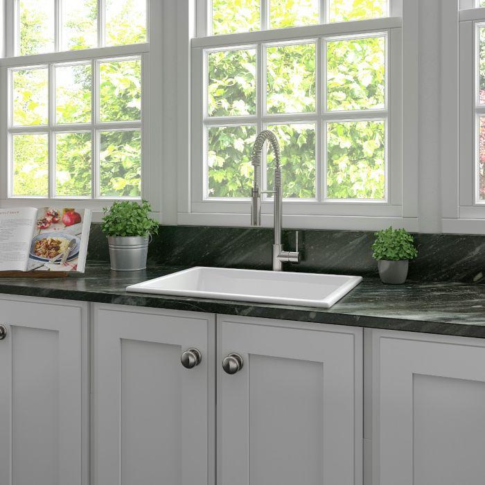 Installed white gloss fireclay single-bowl kitchen sink with faucet on countertop