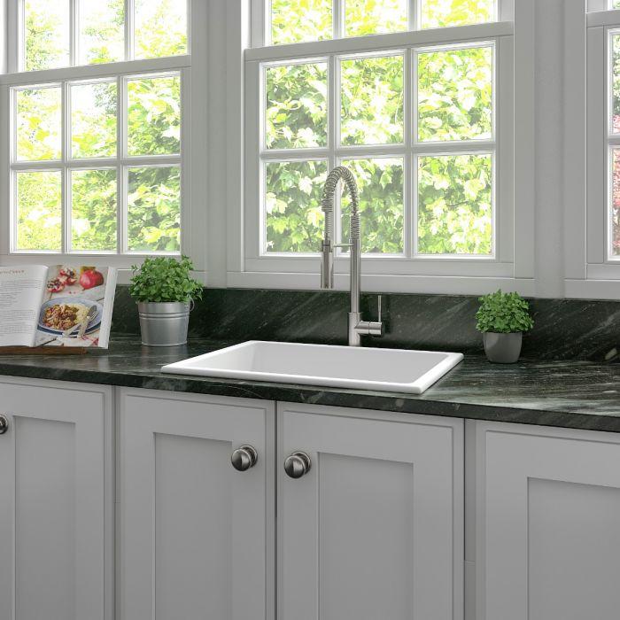 White single-bowl kitchen sink with metal faucet installed on countertop