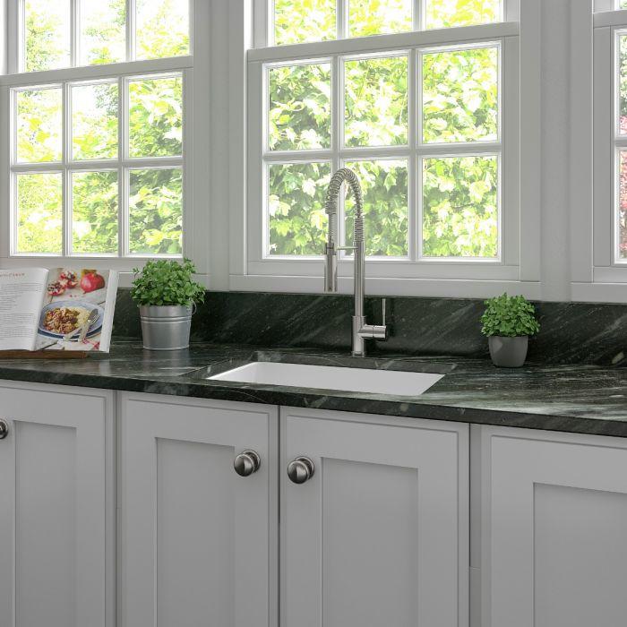 White single-bowl kitchen sink with metal faucet installed in countertop cabinetry