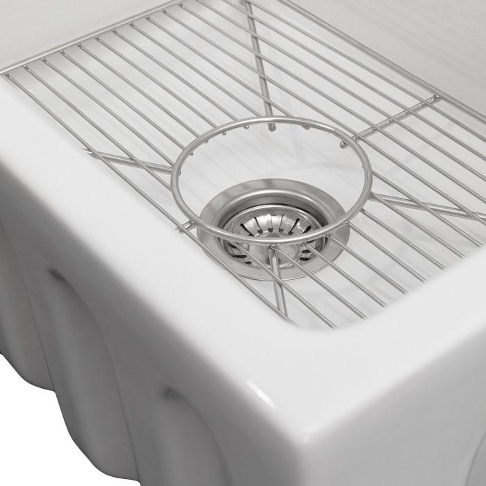 White single-bowl fireclay sink with stainless bottom grid and wire rails