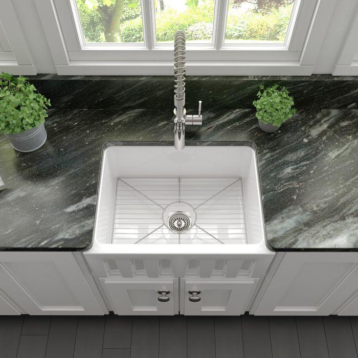 White farmhouse apron-front single-bowl fireclay sink with centered drain and wire grid