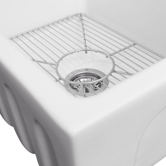 Bottom grid rack with circular drain strainer installed inside white sink basin