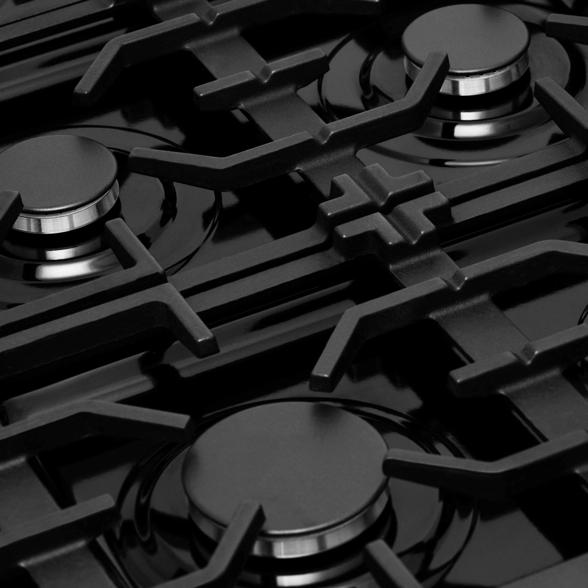 Gas range cooktop with four black grates and round stainless burner caps