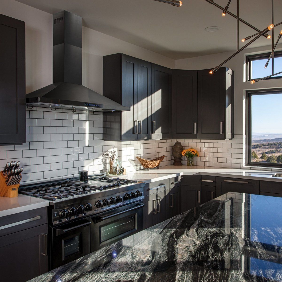 Black dual fuel range with brass burner accents installed in a kitchen.
