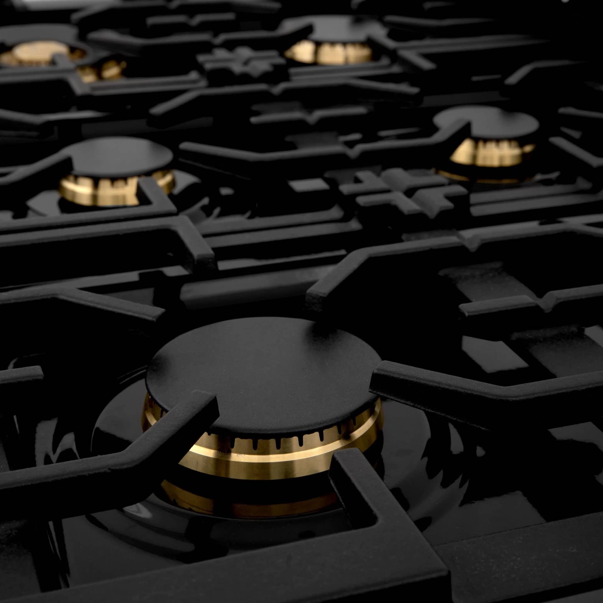 Gas range cooktop close-up with black grates and brass burner rings