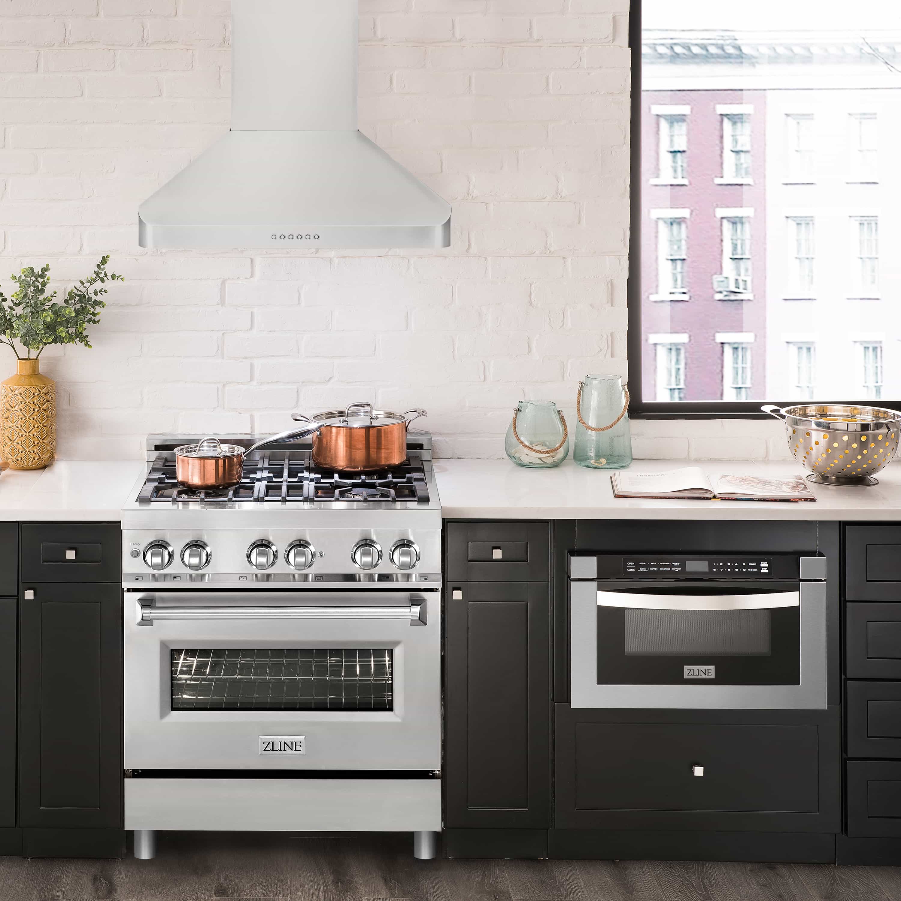 Stainless steel ducted wall-mount range hood above a gas cooktop