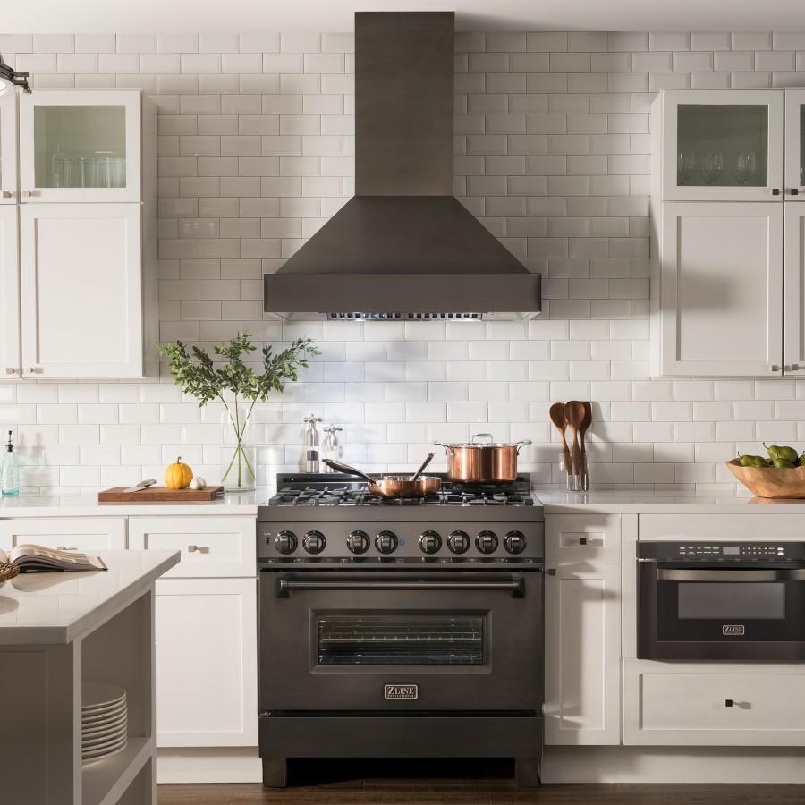 Black wall mount range hood centered over a cooktop in a bright kitchen setting