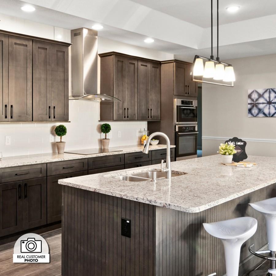 Stainless steel wall mount range hood above cooktop in a modern kitchen.