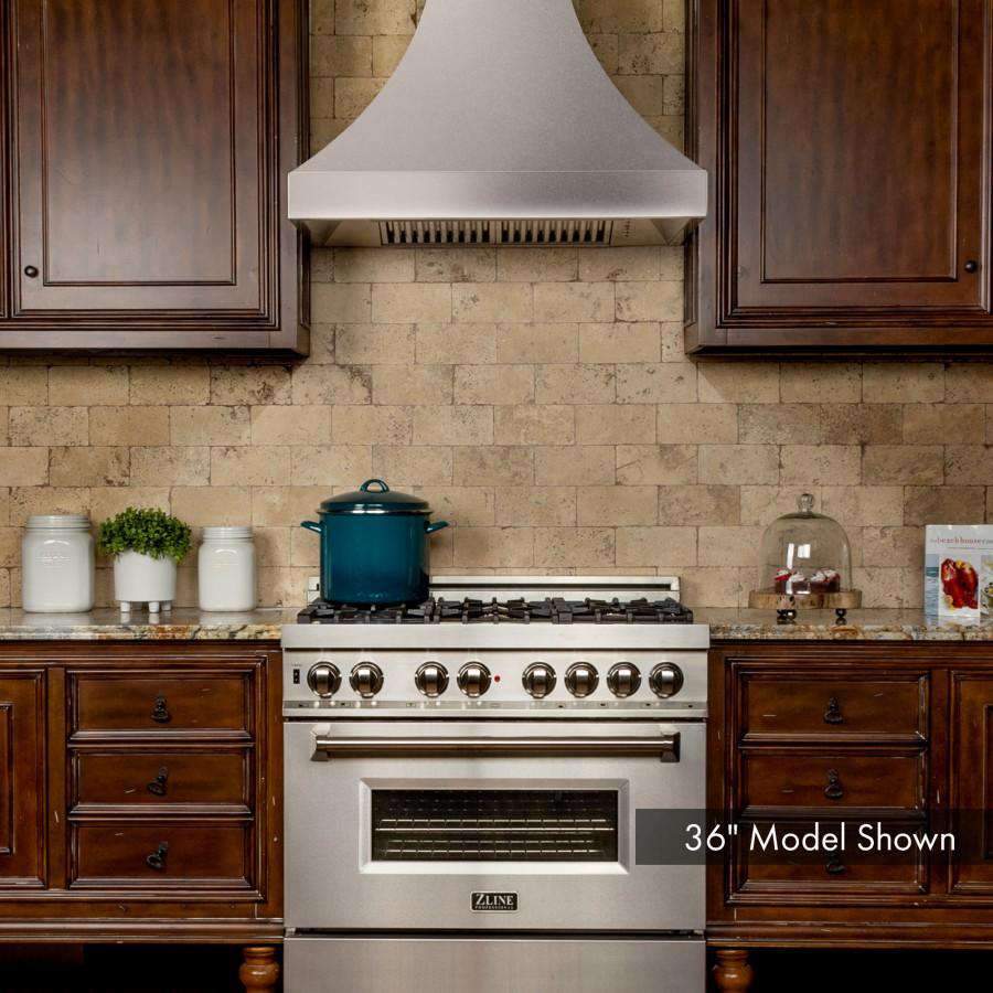 Stainless steel wall range hood mounted above a gas range and built-in oven