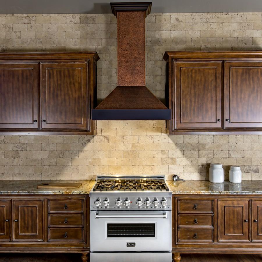 Wall-mounted designer wall range hood with hammered copper-finish chimney and dark vent cover