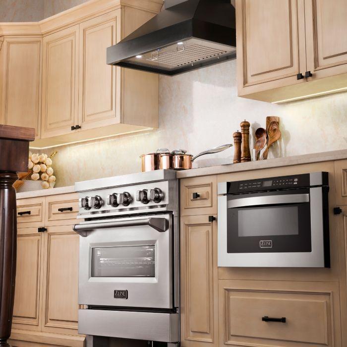 Black chimney range hood above cooktop with stainless baffle filter and lighting