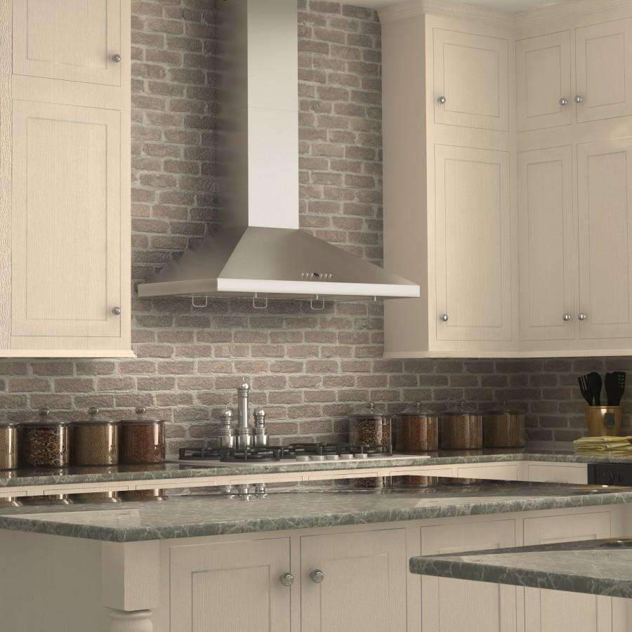 Stainless steel wall-mount convertible range hood above a gas cooktop on brick backsplash.
