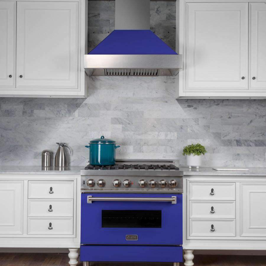 Wall-mount range hood with stainless flue and blue matte shell centered above the range