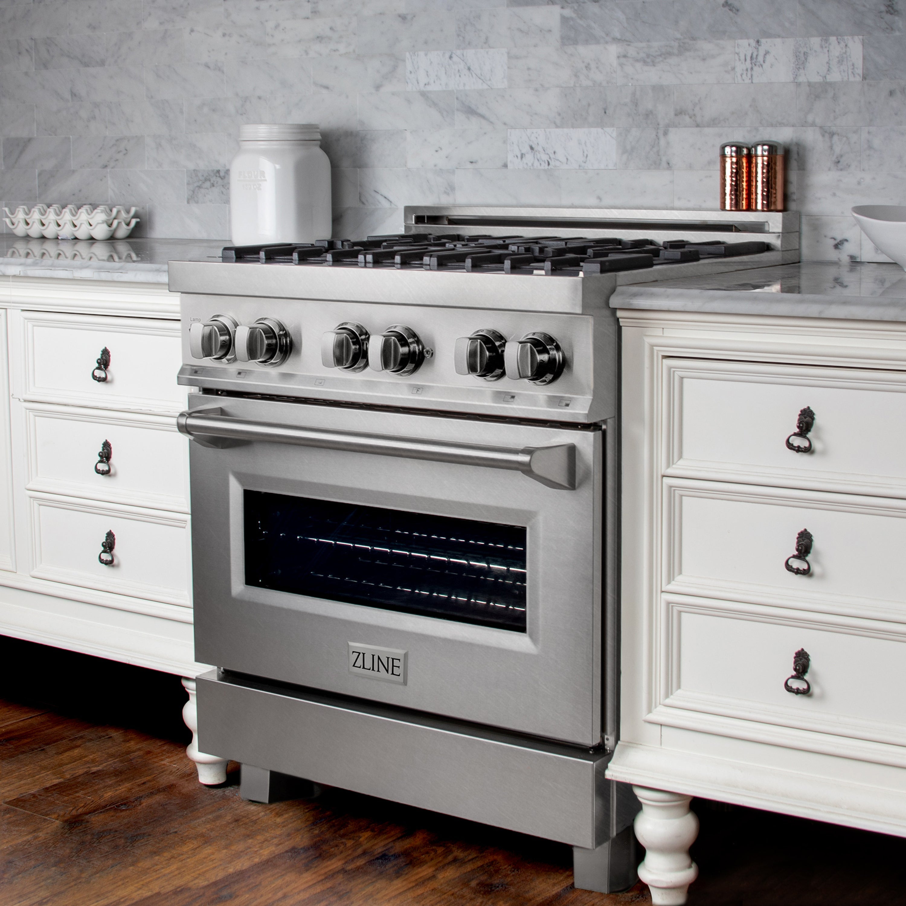 Satin stainless dual fuel range with control knobs, brass burners, and open oven