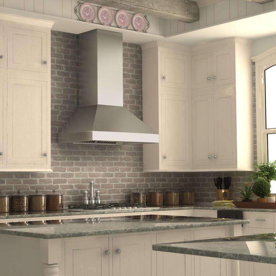 Stainless steel chimney range hood above gas cooktop on brick backsplash