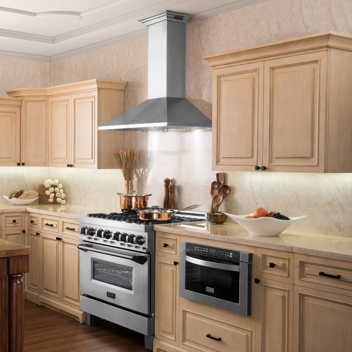 Stainless steel wall-mount range hood above a cooktop and wooden cabinet doors