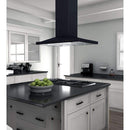 Black island range hood over a countertop cooktop with recessed lighting